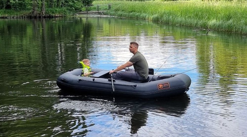 Tēvs ar bērnu airē ARGO piepūšamo laivu ezerā